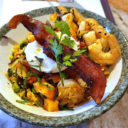 Mouth-watering bowl of rice with shrimp, poached egg, bacon, and veggies