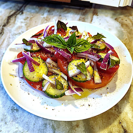 A plate of well-seasoned vegetable salad, highlighting the vibrant color of the red onion, cucumber, and tomato