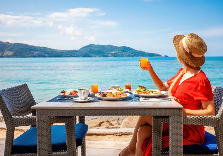 A woman enjoying her meal on a sunny day with ocean view